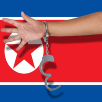 handcuffs with hand on North Korea flag